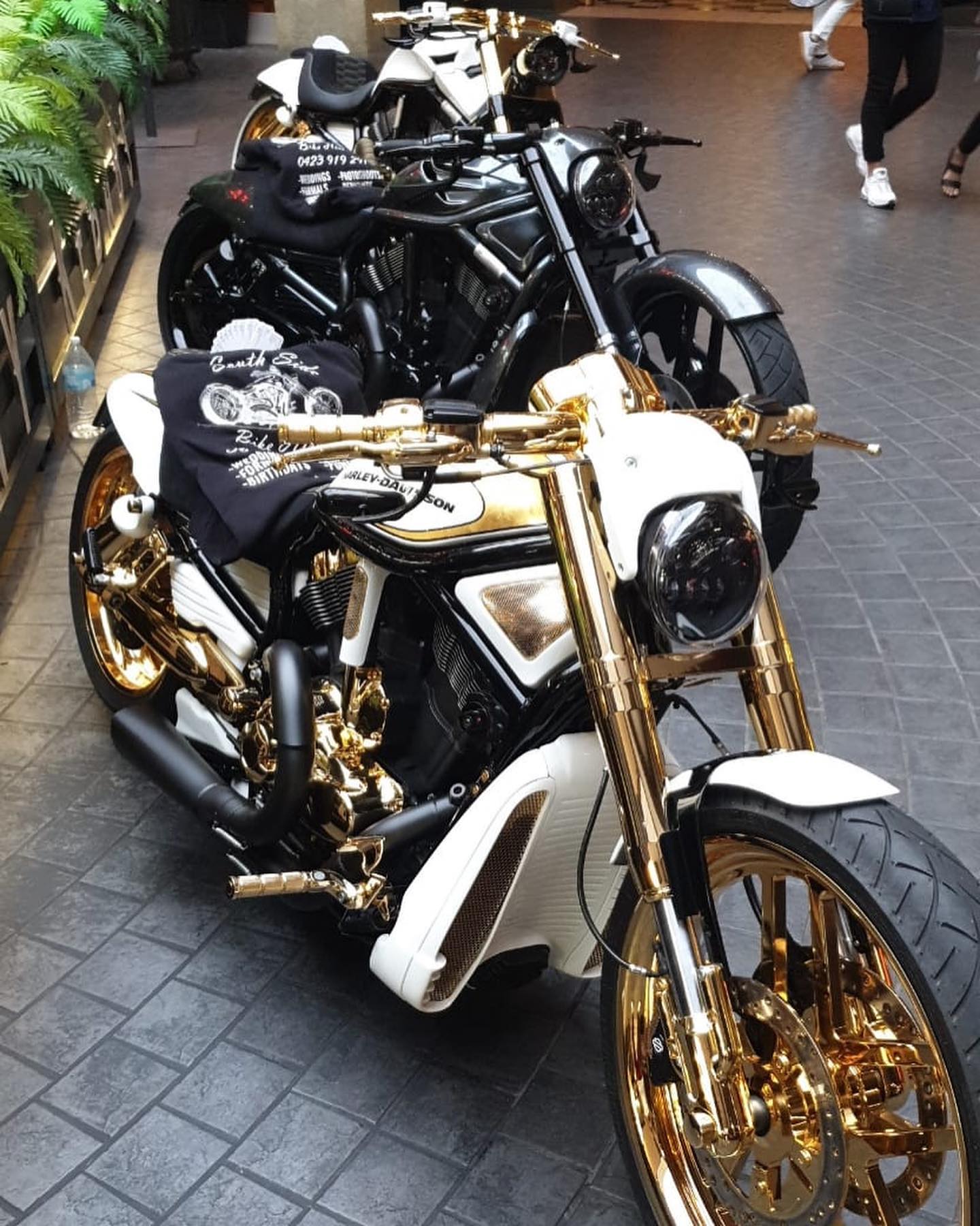 White and gold Harley in front of black Harleys on a paved indoor floor