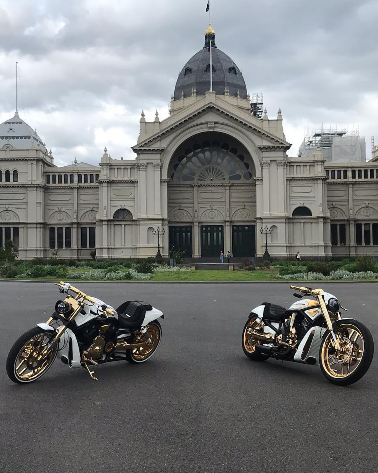 Two gold-trimmed white Harleys parked in front of a domed heritage building