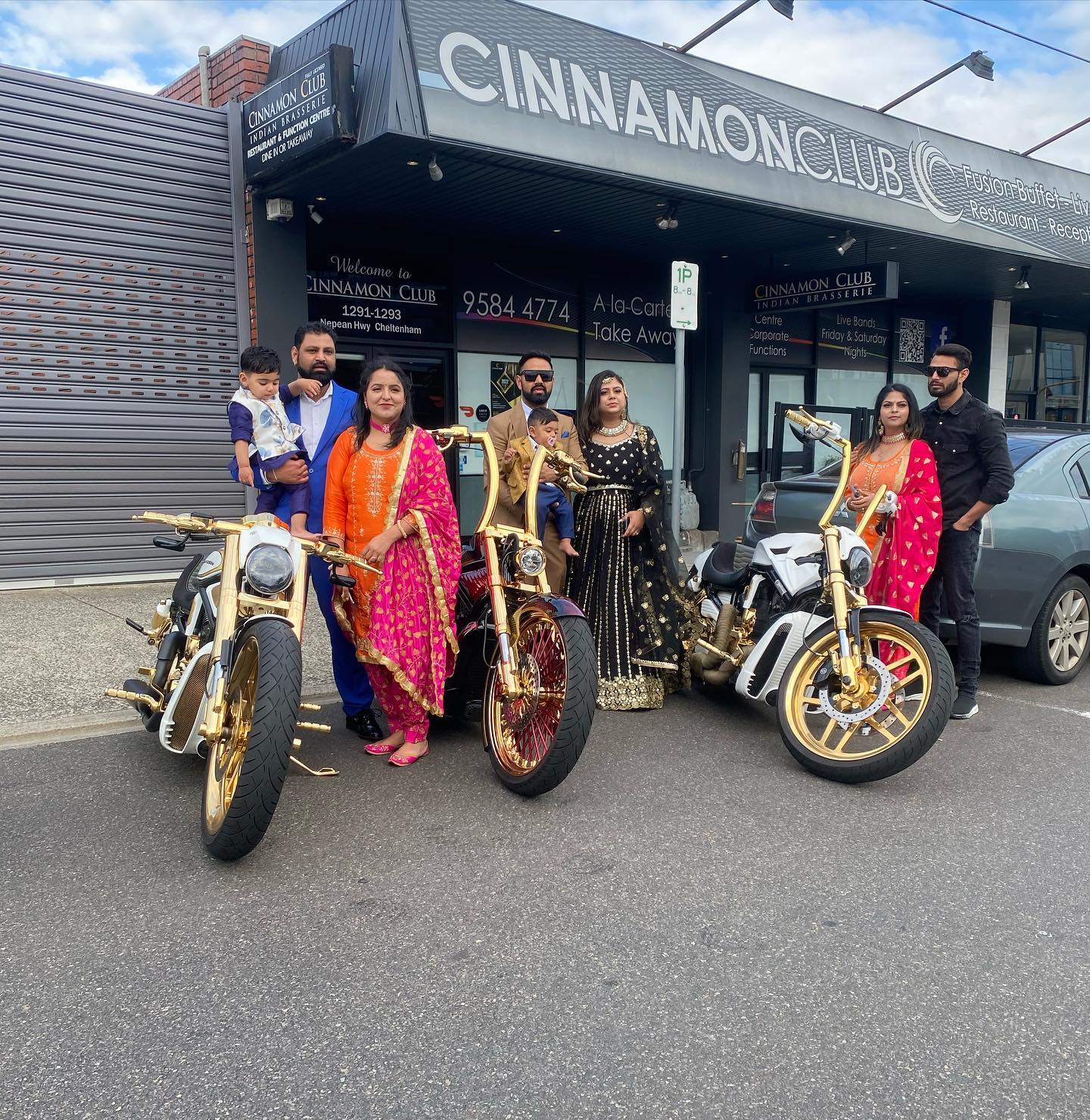 Family in colourful formal wear posing with gold Harleys outside a function venue