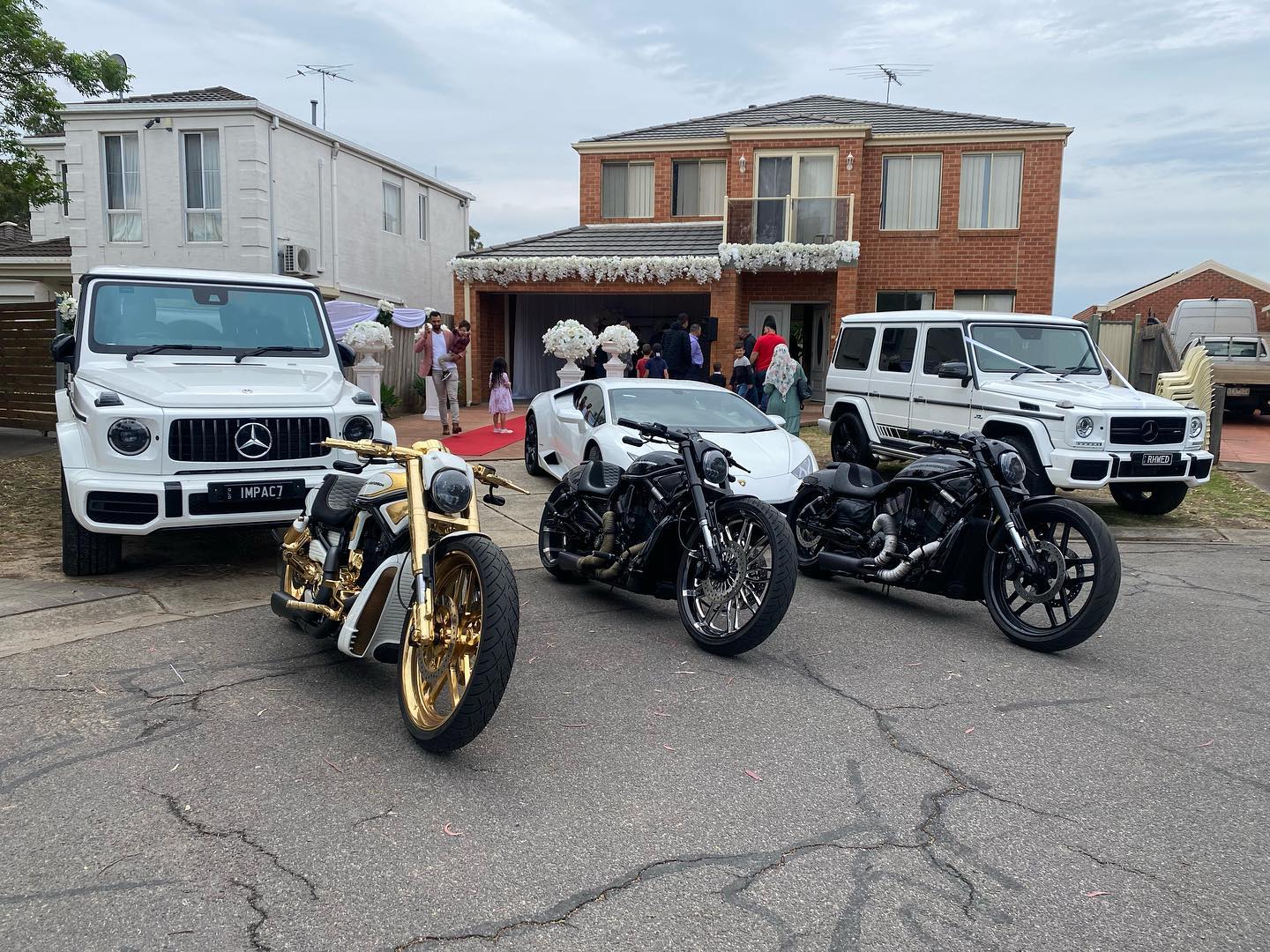 Gold and black Harleys parked in front of a house between two white four-wheel drives