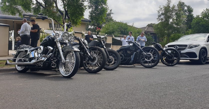 Row of black and chrome Harleys parked along a suburban street