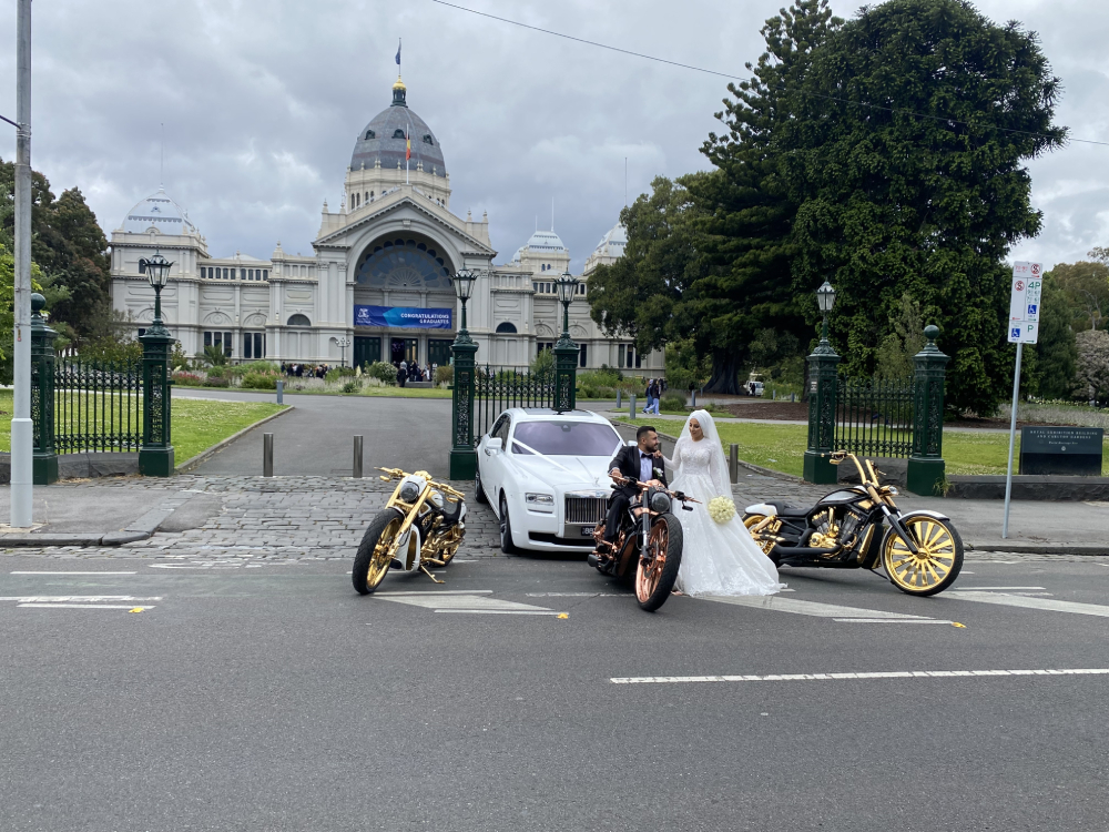 Bride and groom with gold and copper Harleys in front of a domed heritage building