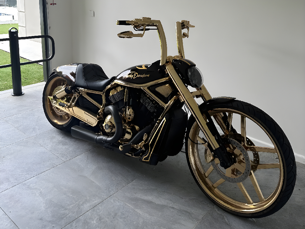 Black and gold Harley with tall gold handlebars parked on a concrete floor