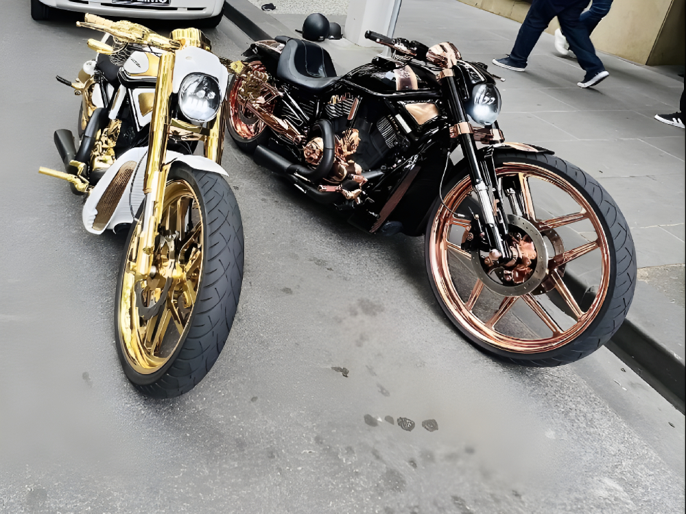 White-and-gold and black-and-copper Harleys parked side by side on a footpath