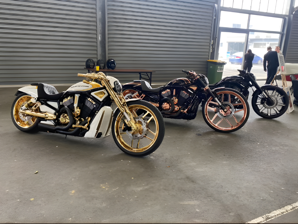 Three custom Harleys with gold and copper wheels parked inside a warehouse