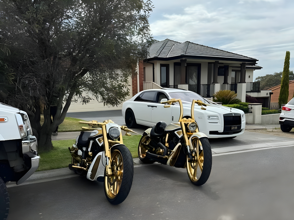 Two gold-trimmed Harleys parked in a street in front of a white luxury car