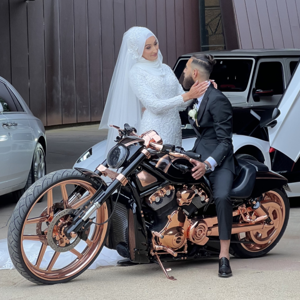 Bride and groom posing on a copper-trimmed black Harley in a laneway