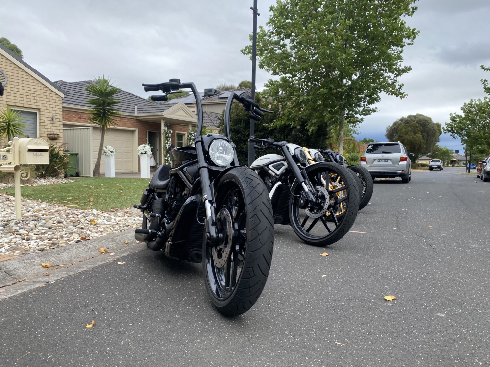 Black Harleys with tall handlebars lined up along a suburban street