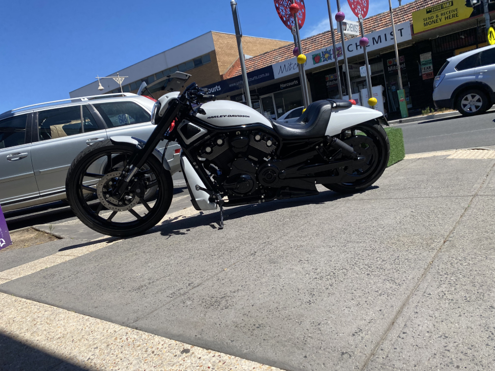 White and black Harley parked on a footpath outside a shopping strip
