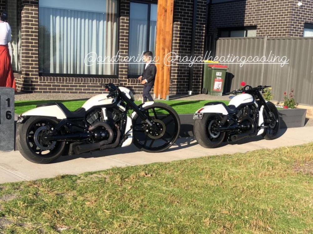Two white and black Harleys parked on a footpath outside a brick house