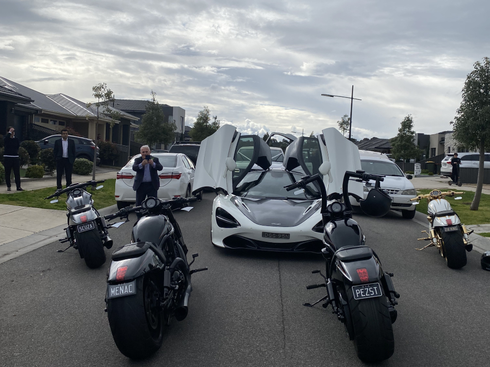 Black Harleys parked around a white sports car with its doors raised