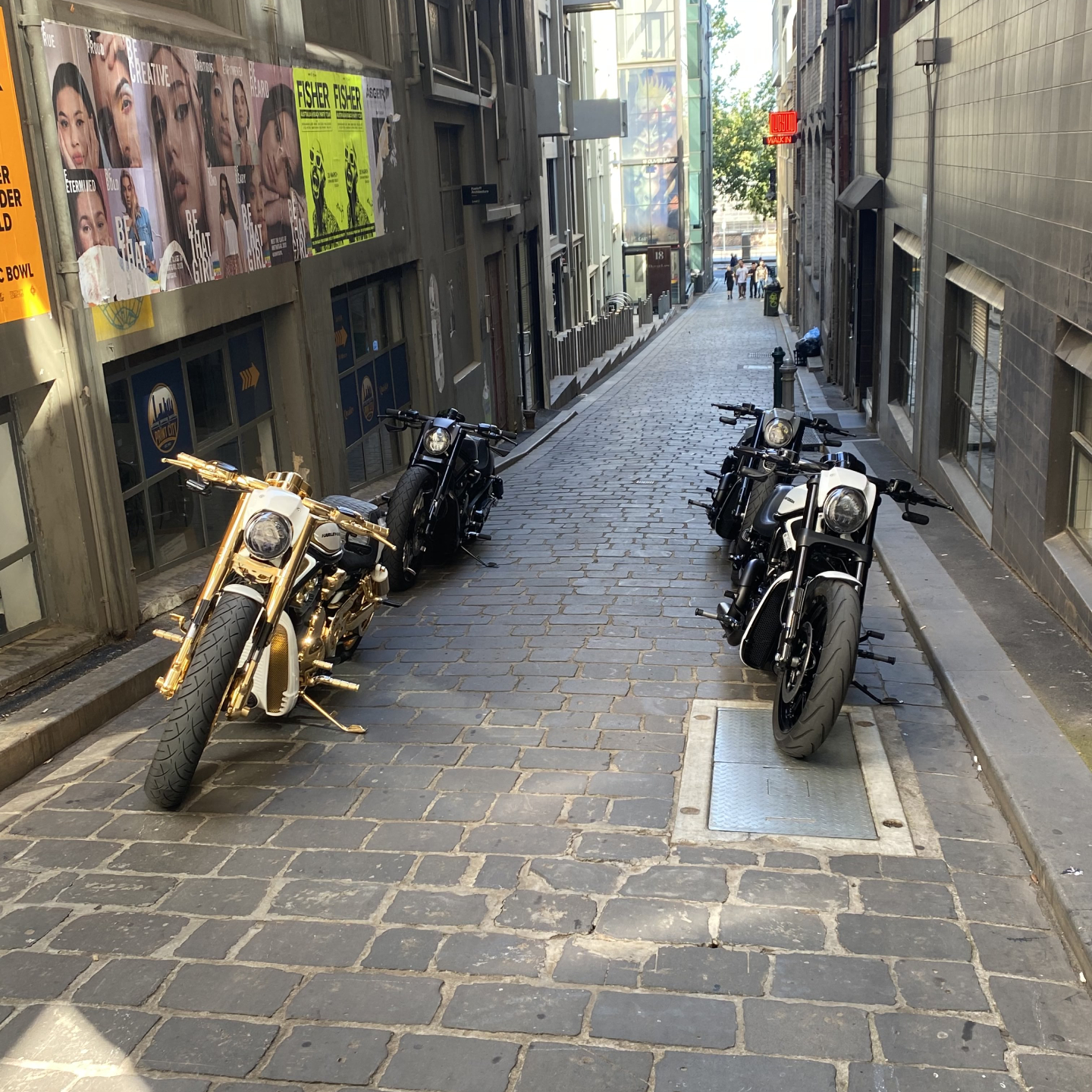 Gold and black Harleys parked along a cobbled city laneway