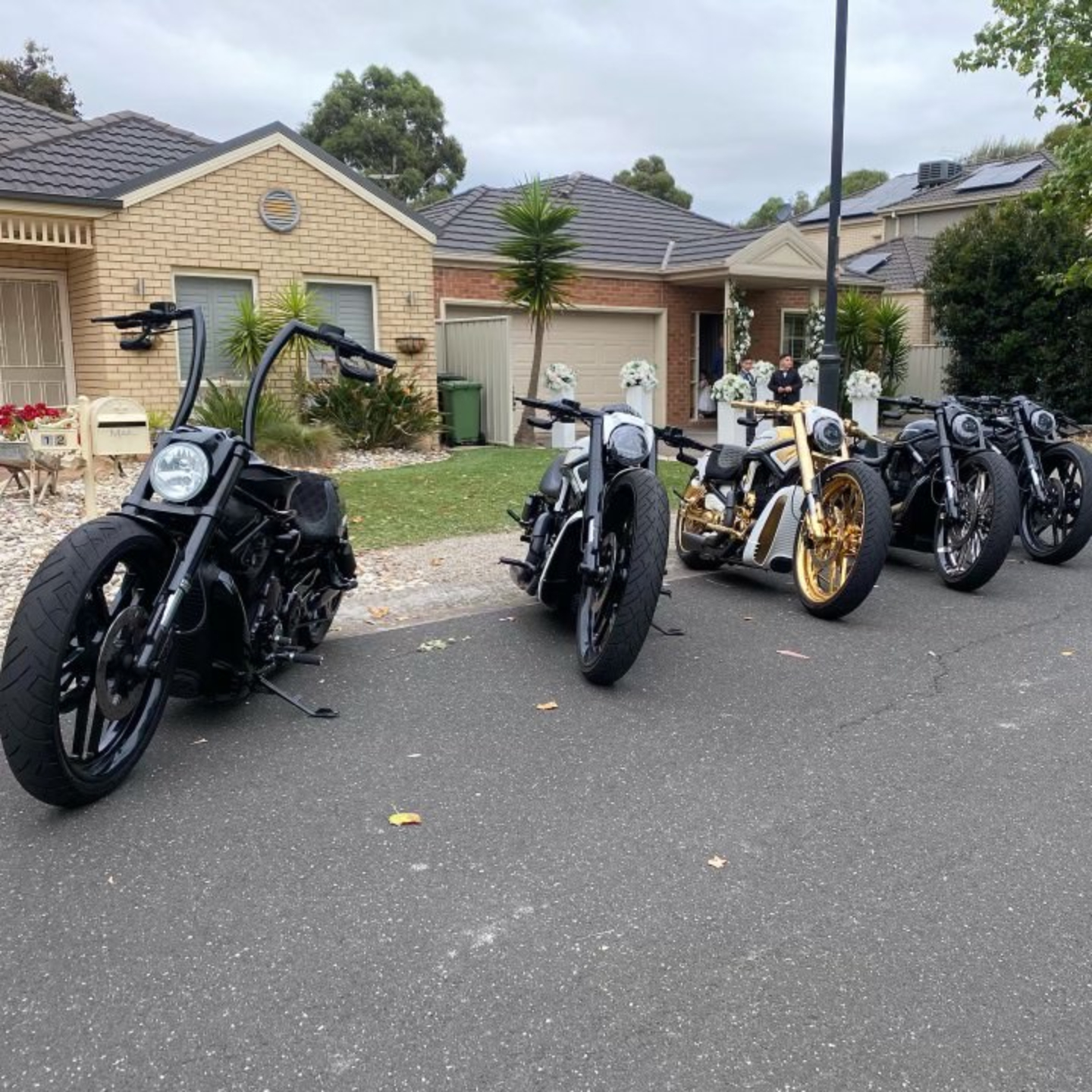 Black Harleys and a gold-trimmed Harley parked in a suburban street
